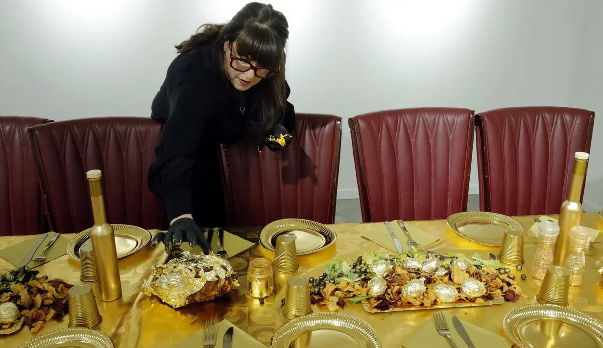 Seniman Prancis, Frederique Lecerf menyiapkan hidangan makan malam bernuasa emas 24 karat di Paris, Prancis, 28 Maret 2019. Lecerf mematok 40 euro per orang untuk sekali mencicipi makanan yang dibalut oleh emas buatannya. (REUTERS/Philippe Wojazer)