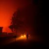 Seorang petugas pemadam kebakaran berjalan melewati rumah-rumah yang terancam oleh kebakaran hutan di Saumos dekat Bordeaux, Prancis barat daya (12/9/2022). Kebakaran yang berlangsung sejak 12 September 2022 telah menyebar sekitar 1800 hektar vegetasi dan hutan di Saumos dan memaksa evakuasi kota dalam konteks suhu tinggi di Gironde. (AFP/Philippe Lopez)