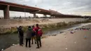 Sekelompok kecil imigran mendiskusikan apakah akan menyeberangi Rio Grande atau tidak dari Ciudad Juarez, Meksiko, dan menyerah kepada Patroli Perbatasan di El Paso, Texas, 18 Desember 2022. Kota-kota perbatasan Texas bersiap menghadapi lonjakan sebanyak 5.000 imigran baru setiap hari yang melintasi perbatasan AS-Meksiko karena pembatasan imigrasi era pandemi berakhir minggu ini. (AP Photo/Andres Leighton)