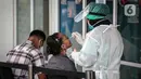 Petugas melakukan tes usap PCR kepada warga di Laboratorium Genomik Solidaritas Indonesia (GSI), Kamis (3/2/2022). Merebaknya varian Omicron membuat sejumlah lokasi tes COVID-19 ramai didatangi warga. (Liputan6.com/Faizal Fanani)