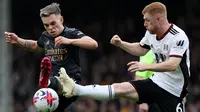 Gelandang Arsenal, Leandro Trossard, berduel dengan gelandang Fulham, Harrison Reed, pada laga pekan ke-27 Premier League 2022/2023 yang berlangsung di Craven Cottage, Minggu (12/3/2023) malam WIB. (AFP/Adrian Dennis)