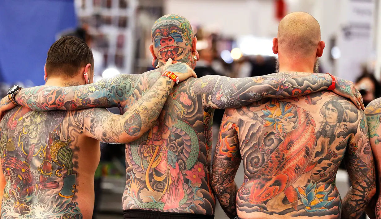 Tiga pria dari Belanda menunjukkan tato di punggung mereka pada hari pertama Konvensi Tattoo Frankfurt di Frankfurt, Jerman (21/4). Ratusan seniman tato ramaikan ajang pertemuan para pecinta seni menggambar tubuh ini. (AP Photo / Michael Probst)