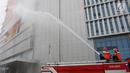 Pemadam kebakaran menyemprotkan air ke dalam gedung saat simulasi bencana di Gedung Graha BNPB, Jakarta, Kamis (26/4). (Liputan6.com/Arya Manggala)