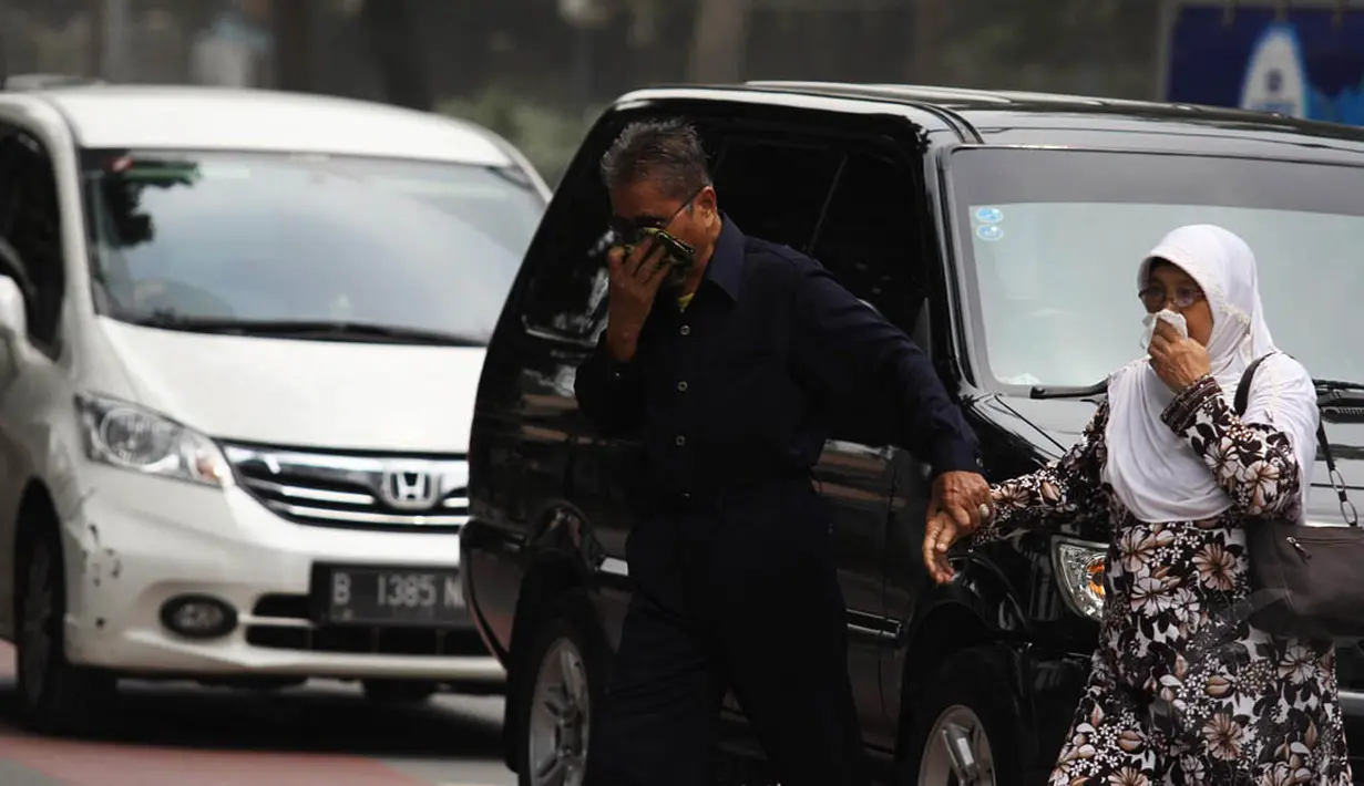 Para pengguna jalan terpaksa menutupi hidung dengan tangan saat melintasi Jalan Kemukus, Tamansari, Jakarta, Senin (24/11/2014). (Liputan6.com/Faizal Fanani)