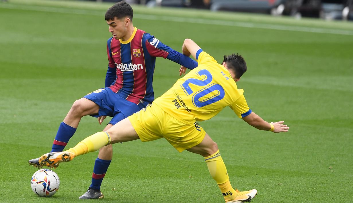 Pedri (kiri) yang merangsek ke kotak penalti lawan dijatuhkan oleh bek Cadiz dan wasit pun langsung menunjuk titik putih. (Foto: AFP/Josep Lago)