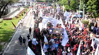 Massa buruh berjalan memasuki kawasan Jalan Medan Merdeka Barat, Senin (1/5). Aksi perayaan Hari Buruh Internasional oleh ribuan buruh tertahan di depan Kementerian Pariwisata akibat penutupan Jalan medan Merdeka Barat. (Liputan6.com/Helmi Fithriansyah)