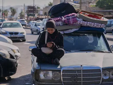 Seorang wanita pengungsi memeriksa ponselnya sambil menunggu untuk kembali ke desanya setelah pengumuman kesepakatan gencatan senjata awal antara Amerika Serikat dan Iran, di kota pelabuhan selatan Sidon, Lebanon, Senin 15 Juni 2026. (AP Photo/Mohammed Zaatari)