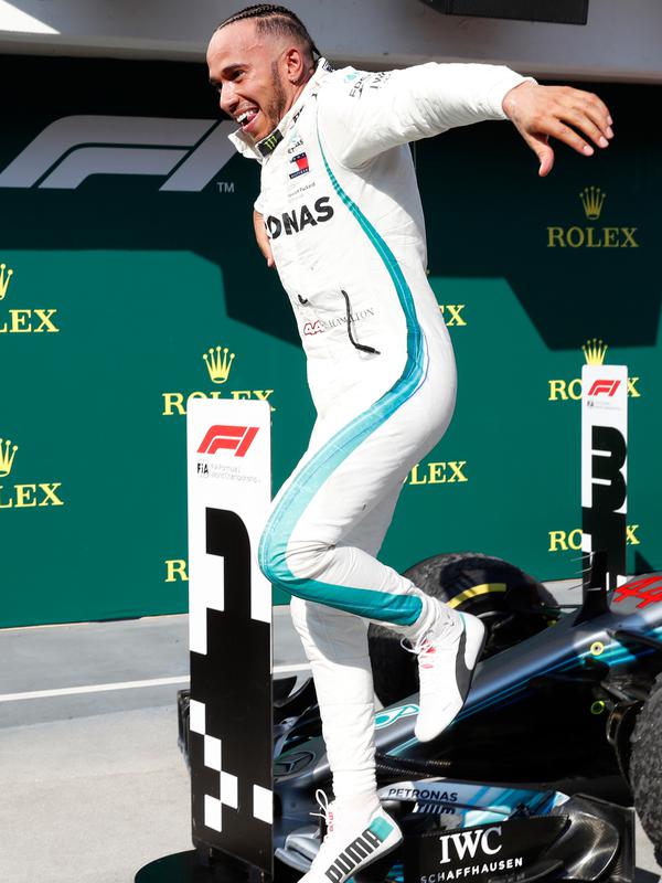 Lewis Hamilton melompat dari mobilnya merayakan kemenagan menjuarai GP Hungaria di Sirkuit Hungaroring, Mogyorod, (29/7). Kemenangan ini sekaligus menempatkan Hamilton berada di puncak klasemen. (AP Photo/Laszlo Balogh)