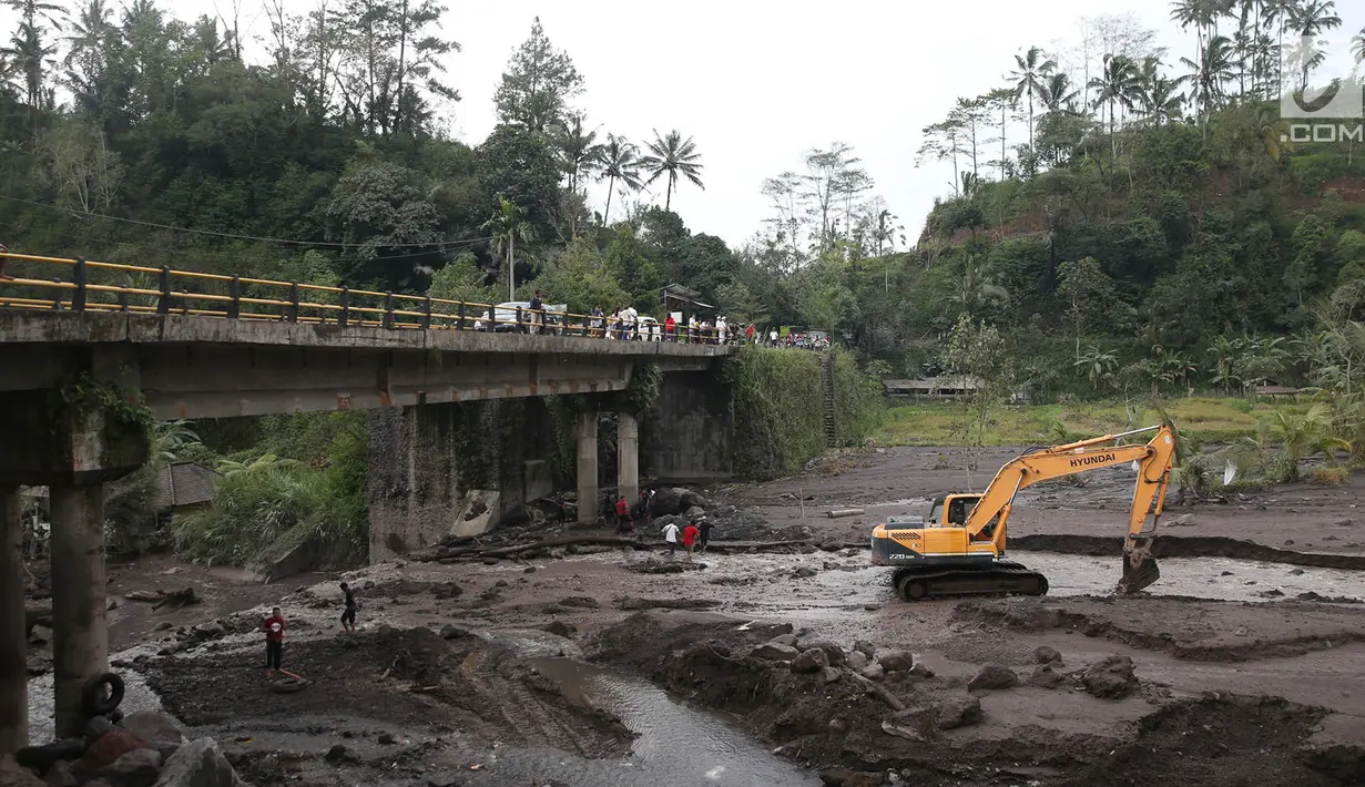 Warga menyaksikan saat alat berat mengeruk material lahar dingin di Sungai Yeh Sah, Rendang, Bali, Minggu (3/12). Sebelumnya, pada Sabtu (2/12/2017) lahar dingin dari Gunung Agung menggenangi Sungai Yeh Sah. (Liputan6.com/Immanuel Antonius)