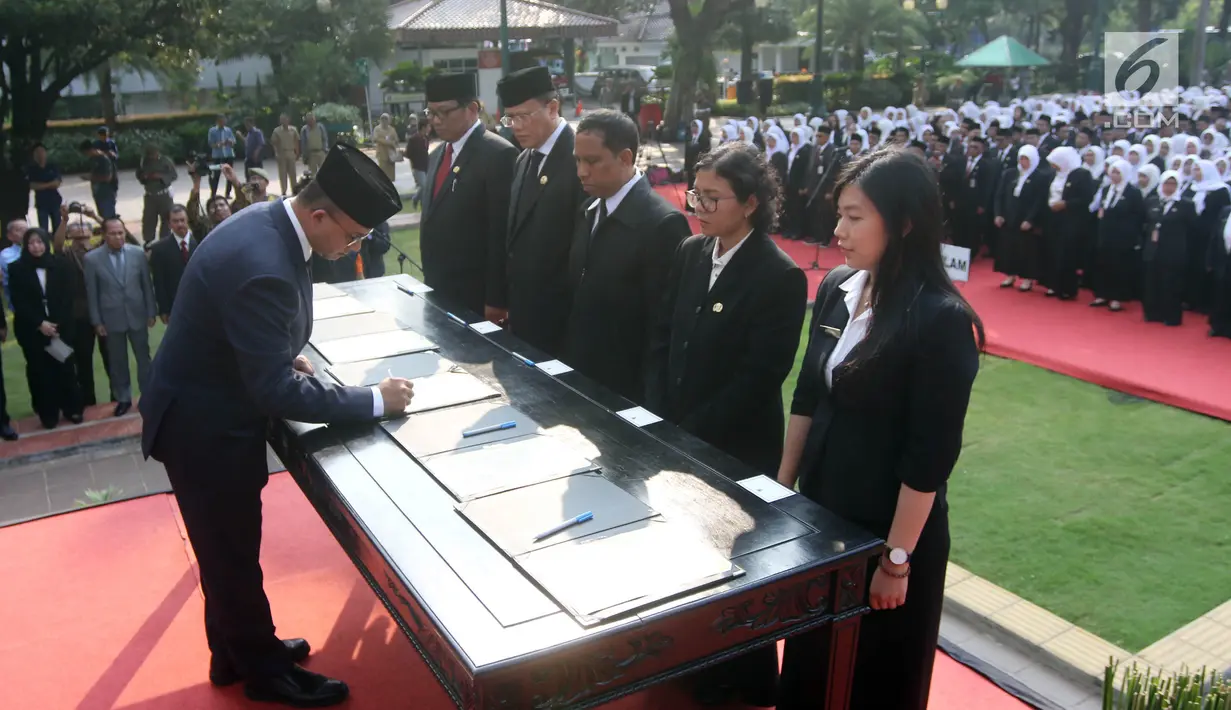 Gubernur DKI Jakarta Anies Baswedan menandatangani berkas saat melantik pejabat fungsional di halaman Balai Kota Jakarta DKI, Senin (4/6). Sebanyak 916 pejabat fungsional yang dilantik terdiri dari berbagai jenis pengangkatan. (Liputan6.com/Arya Manggala)