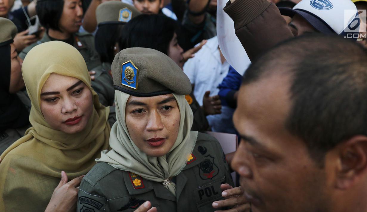 Sejumlah Satpol PP wanita berhadapan dengan petugas keamanan di depan Hotel Alexis, Jakarta, Kamis (29/3). Ibu-ibu personel Satpol PP bertugas untuk memastikan tidak ada kegiatan usaha apapun di Hotel Alexis. (Liputan6.com/Immanuel Antonius)