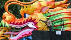 Seorang pekerja mempersiapkan struktur kepala naga dalam persiapan untuk Tahun Baru Imlek yang akan datang di sekitar jalur pengamatan hutan Supertrees di Gardens by the Bay, Singapura, pada 15 Januari 2024. (Roslan RAHMAN/AFP)