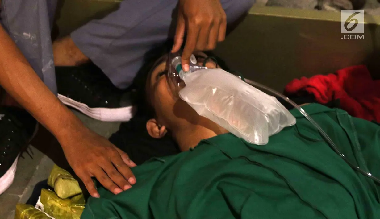 Seorang pria mendapat perawatan medis setelah menjadi korban dalam demonstrasi berujung ricuh di Pejompongan, Jakarta, Rabu (25/9/2019). Sebelumnya, ribuan pelajar yang melangsungkan demonstrasi di Gedung DPR terlibat bentrok dengan polisi. (Liputan6.com/Helmi Fithriansyah)