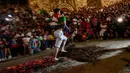 Seorang pria membawa anak lelaki di punggungnya sambil berjalan di atas bara api selama malam San Juan di San Pedro Manrique, Spanyol Utara, Minggu (24/6). Tradisi kuno Spanyol ini diperingati untuk menyambut musim panas. (AP Photo/Alvaro Barrientos)