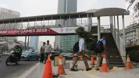 Pejalan kaki saat akan menggunakan jembatan penyeberangan orang (JPO) di Bundaran HI, Jakarta, Selasa (24/7). Pemprov DKI berencana merobohkan JPO tersebut karena menghalangi pandangan ke Patung Selamat Datang. (Liputan6.com/Arya Manggala)