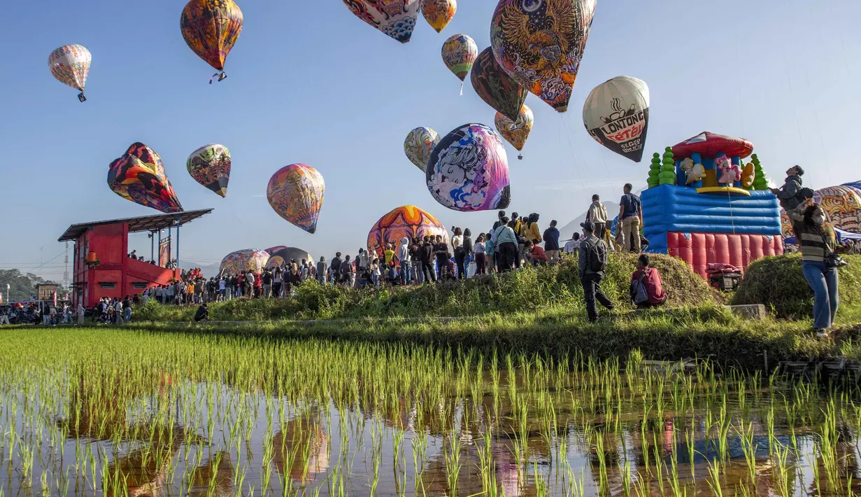 Festival juga bagian dari perayaan Syawalan untuk memeriahkan hari kemenangan. Tampak dalam foto, para pengunjung menyaksikan balon udara yang dihiasi motif tradisional sebelum diluncurkan selama festival tahunan yang diadakan untuk merayakan Hari Raya Idul Fitri, di desa Semayu, Wonosobo, Jawa Tengah pada Senin 23 Maret 2026. (DEVI RAHMAN/AFP)