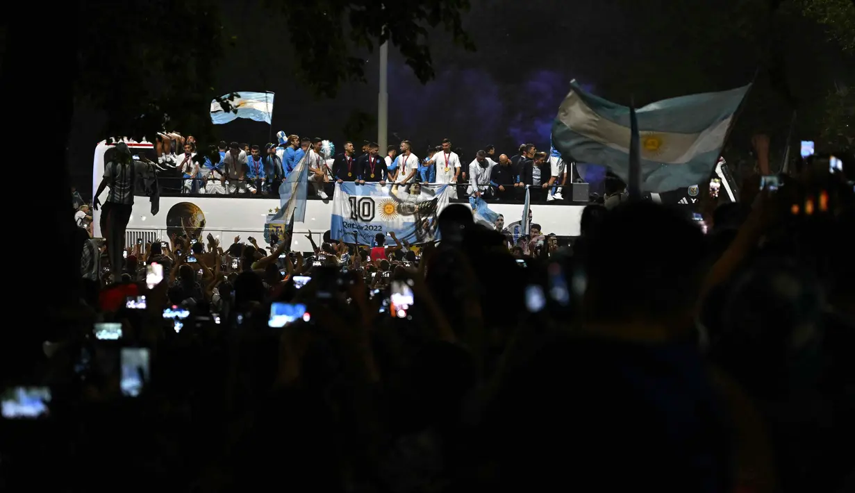 Para pemain Argentina melakukan selebrasi di atas bus saat meninggalkan Bandara Internasional Ezeiza dalam perjalanan menuju pusat pelatihan Asosiasi Sepak Bola Argentina (AFA) setelah menjuarai Piala Dunia Qatar 2022 di Ezeiza, provinsi Buenos Aires, Argentina pada 20 Desember 2022. (AFP/Luis Robayo)