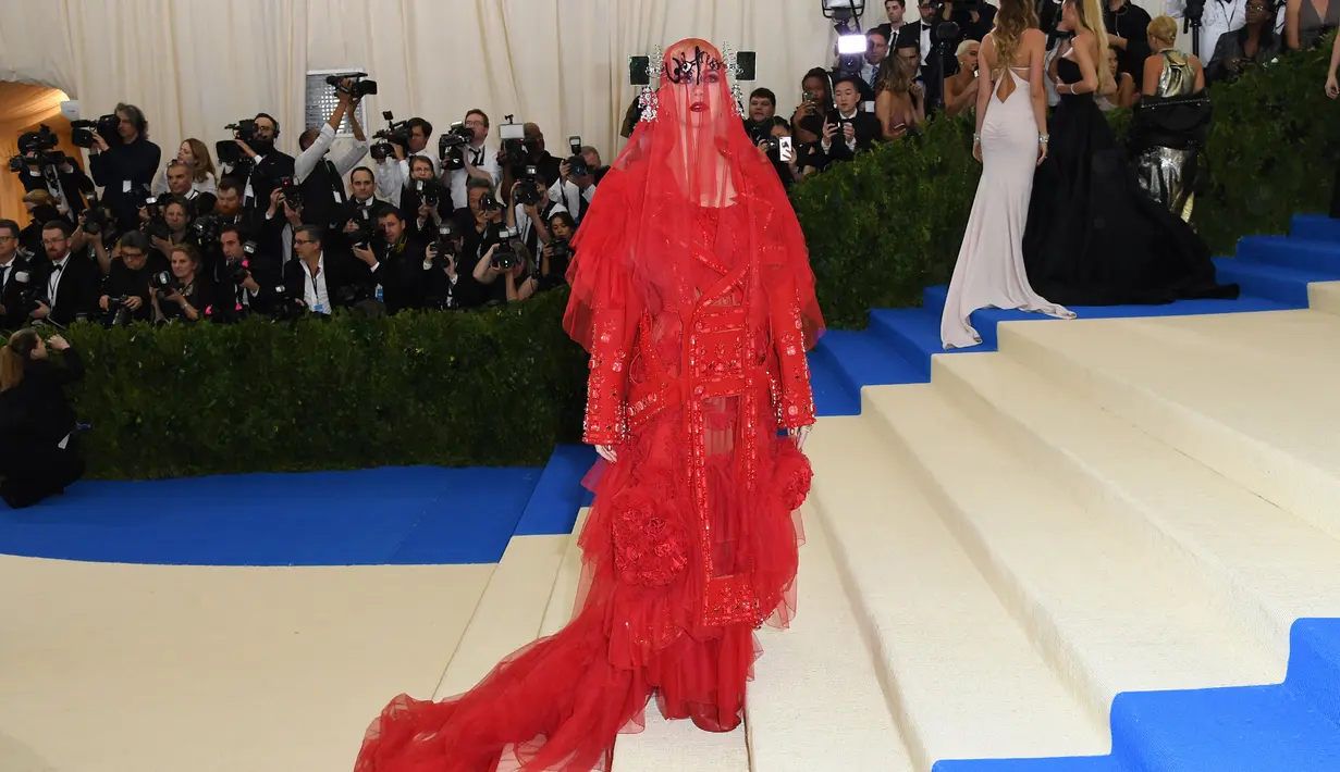 Katy Perry saat menghadiri Met Gala 2017 di Metropolitan Museum of Art, New York (1/5). Dalam ajang ini banyak selebritas yang menggunakan gaun-gaun unik, seperti Katy yang mengenakan gaun serba merah dengan atribut kepala. (AFP Photo/Angela Weiss)