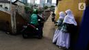 Pengendara sepeda motor melintasi jalur alternatif saat anak sekolah berjalan di belakang Kompleks Patra Jasa, Jakarta Selatan, Rabu (1/3/2023). Jalur alternatif seperti gang, jalan kecil, maupun jalan tembusan menjadi pilihan bagi pengendara sepeda motor untuk menghindari kemacetan di jalan-jalan protokol Ibu Kota. (Liputan6.com/Johan Tallo)