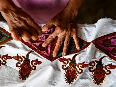 Seorang pekerja membuat desain batik di sebuah bengkel di Banda Aceh, Aceh, Rabu (13/10/2021). Batik Aceh memiliki ciri khas tersendiri, yaitu menggunakan perpaduan unsur alam dan budaya dari masyarakat Aceh sendiri. (Chaideer MAHYUDDIN/AFP)