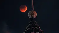 Bulan berwarna merah darah terlihat di atas Menara Petronas saat terjadinya fenomena gerhana bulan total  di Kuala Lumpur, Malaysia, Sabtu (28/7). Gerhana bulan terlama pada abad ini dapat disaksikan di seluruh dunia dengan mata telanjang. (AP/Yam G-Jun)