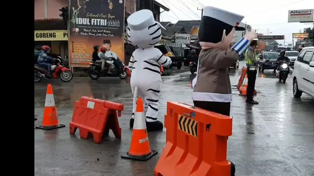 Dengan karekter menghibur badut Polres Tasikmalaya, Jawa Barat nampak asik menghibur pemudik yang melintas Tasikmalaya. (Liputan6.com/Jayadi Supriadin)