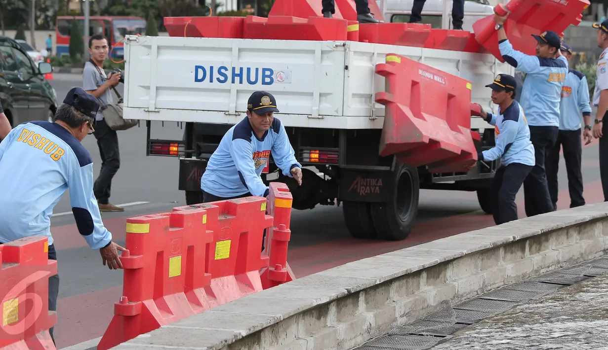 Petugas Dinas Perhubungan menata pembatas jalan untuk menutup sejumlah titik di kawasan Bundaran HI, Jakarta, (31/12). Gubernur DKI Jakarta Basuki Tjahaja Purnama mengatakan perayaan tahun baru akan dibagi dibeberapa wilayah. (Liputan6.com/Angga Yuniar)