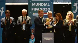 Presiden Paraguay, Alejandro Dominguez (tengah) memegang replika trofi Piala Dunia saat penunjukkan Argentina, Paraguay, dan Uruguay sebagai negara tuan rumah Piala Dunia FIFA 2030 selama Kongres virtual FIFA di Luque, Paraguay pada 11 Desember 2024. (AFP/Daniel Duarte)