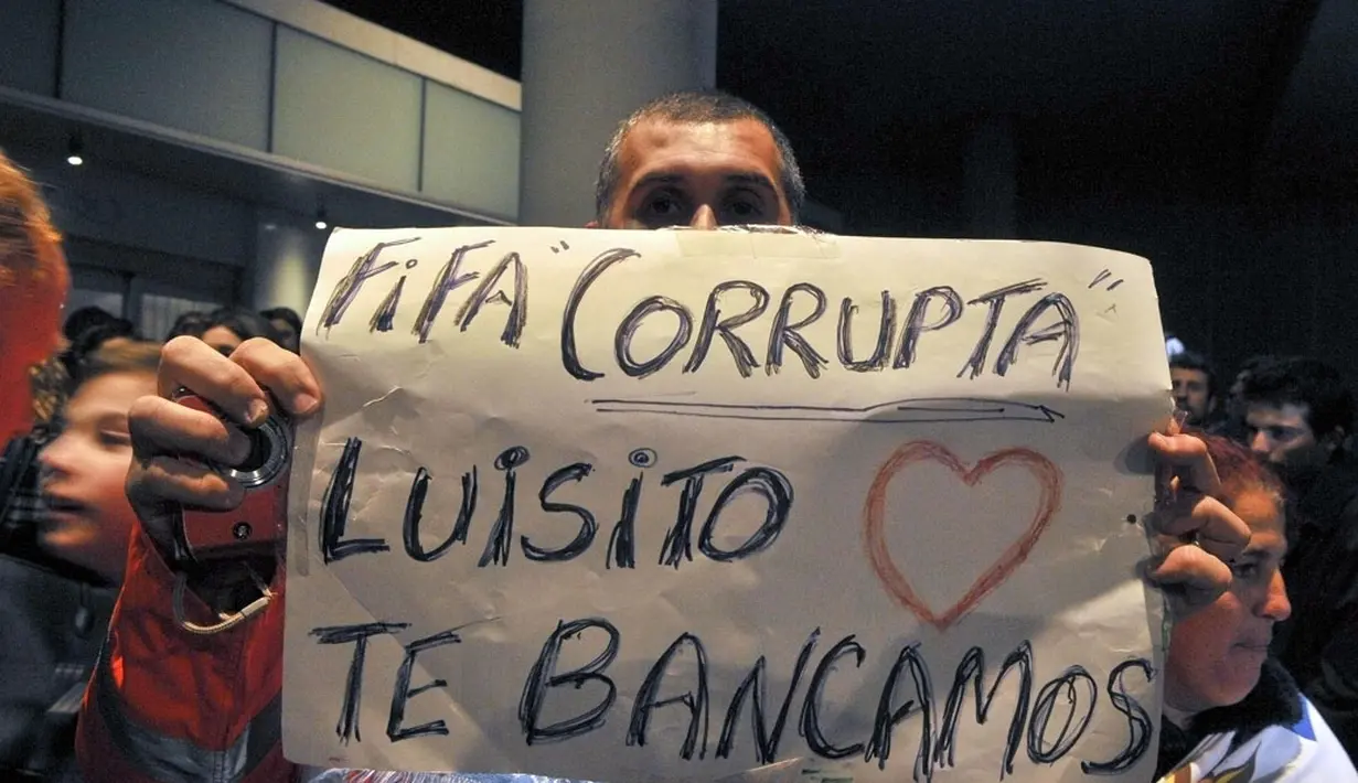 Sambil menanti kedatangan Luis Suarez di Bandara Montevideo, Carrasco, (26/6/2014), salah satu warga Uruguay membentangkan tulisan berbunyi "FIFA korup - Luis, kita mencintai dan mendukungmu". (REUTERS/Carlos Pazos)