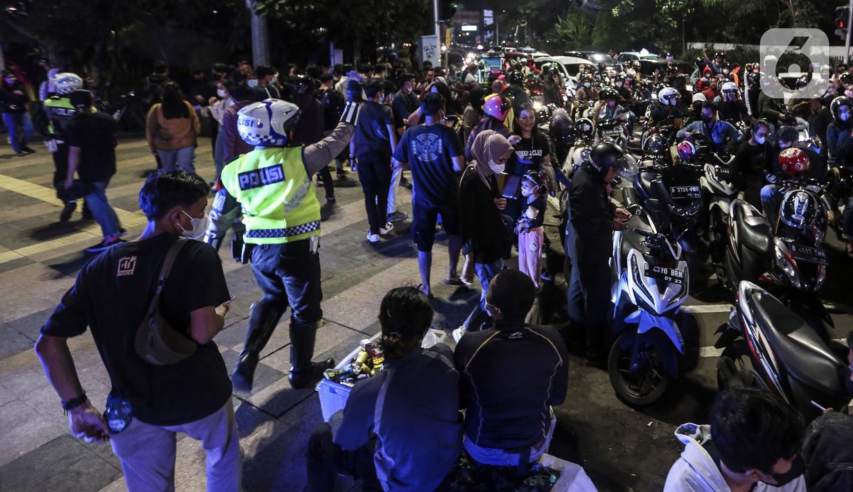 Polisi membubarkan kerumunan warga saat perayaan malam Tahun Baru di Jakarta, Jumat (31/12/2021). Polda Metro Jaya melakukan pengendalian mobilitas Crowd Free Night (malam bebas keramaian) dengan membubarkan warga yang nekat keluar rumah dan tidak mematuhi aturan. (Liputan6.com/Johan Tallo)