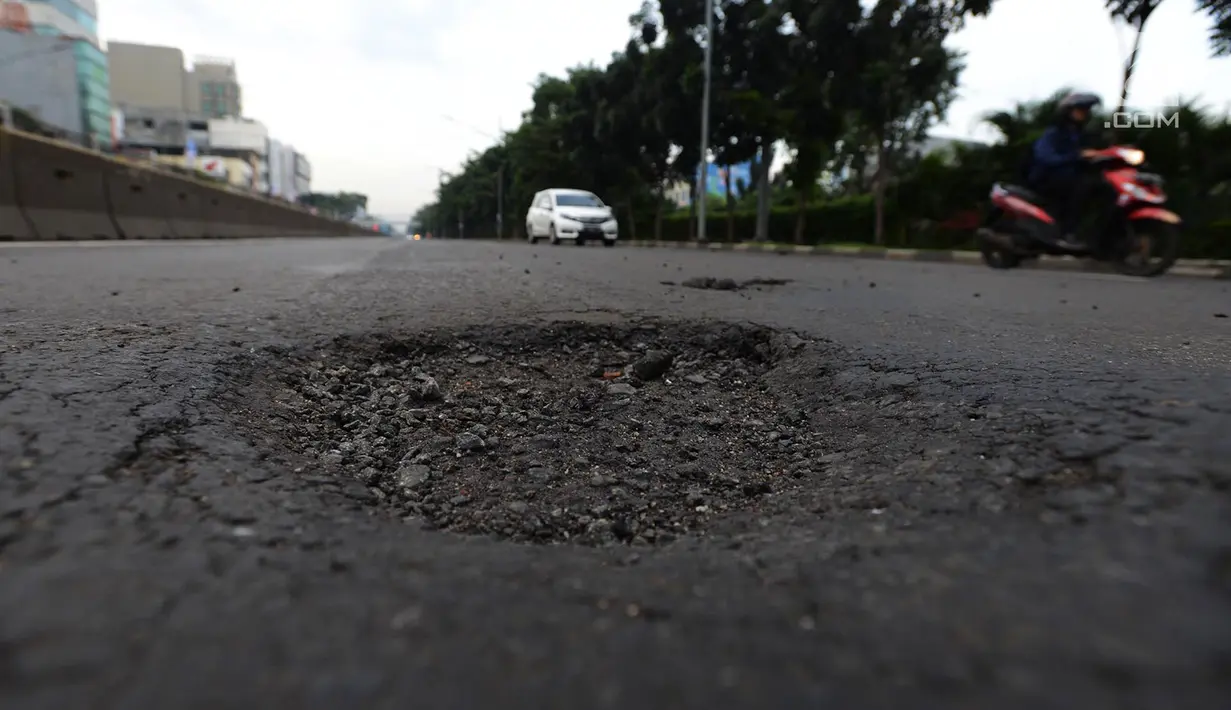 Kendaraan melintasi jalan berlubang di Jalan Gunung Sahari, Jakarta, Selasa (9/4). Meskipun sudah dilakukan penambalan, jalan raya tersebut sering rusak akibat beban kendaraan yang melintas di atasnya dan intensitas hujan yang belakangan ini cukup tinggi. (merdeka.com/Imam Buhori)