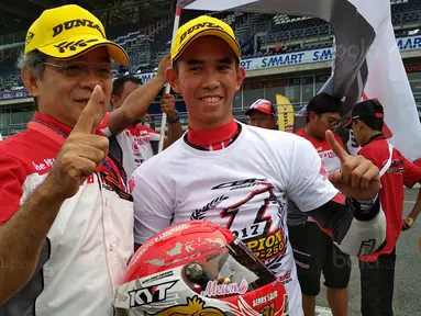 Presiden Direktur Astra Honda Racing Team, Toshiyuki inuma foto bersama Gerry Salim di Sirkuit Buriram, Thailand Sabtu (2/12/2017). Gerry Salim menjadi rider Indonesia pertama yang menjuarai ARRC kelas Asia Production 250. (Bola.com/Muhammad Wirawan)