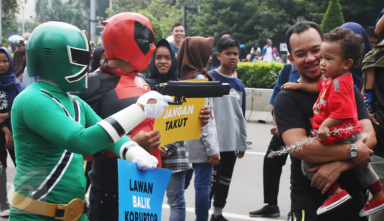 Seperhero menyapa warga saat melakukan aksi teaterikal di Bundaran HI, Jakarta, Minggu (16/4). Dalam aksi teaterikal tersebut para superhero menyuarakan untuk terus mendukung KPK. (Liputan6.com/Angga Yuniar)