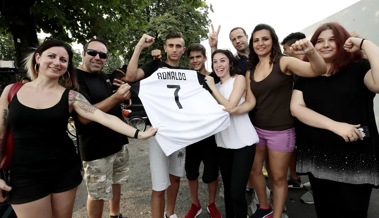 Suporter memegang jersey Juventus atas nama Cristiano Ronaldo saat merayakan transfer sang megabintang di Turin, Selasa (10/7). Juventus mendatangkan Ronaldo dengan biaya 100 juta euro atau Rp 1,68 triliun. (AFP PHOTO / Isabella Bonottovv)