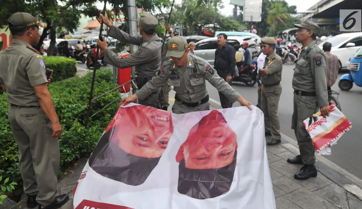 Suasana saat petugas Satpol PP membongkar spanduk parpol yang dipasang di Cempaka Putih, Jakarta (21/3). Panwaslu Cempaka Putih menertibkan spanduk tersebut karena melanggar UU Nomor 7 Tahun 2017 tentang Pemilihan Umum. (Merdeka.com/Arie Basuki)
