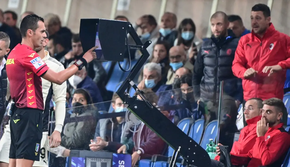 Wasit Marco Di Bello memeriksa VAR sebelum memberikan penalti pada pertandingan Liga Italia Serie A antara AC Milan dan Atalanta di Stadion Gewiss, Bergamo, Italia, 3 Oktober 2021. AC Milan menang 3-2 atas Atalanta. (MIGUEL MEDINA/AFP)