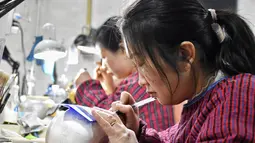 Sejumlah pekerja menggambar pola pada perkakas emas dan perak di sebuah bengkel kerja di Kota Baimasi di Distrik Luolong, Luoyang, Provinsi Henan, China tengah (11/11/2020). (Xinhua/Han Chaoyang)