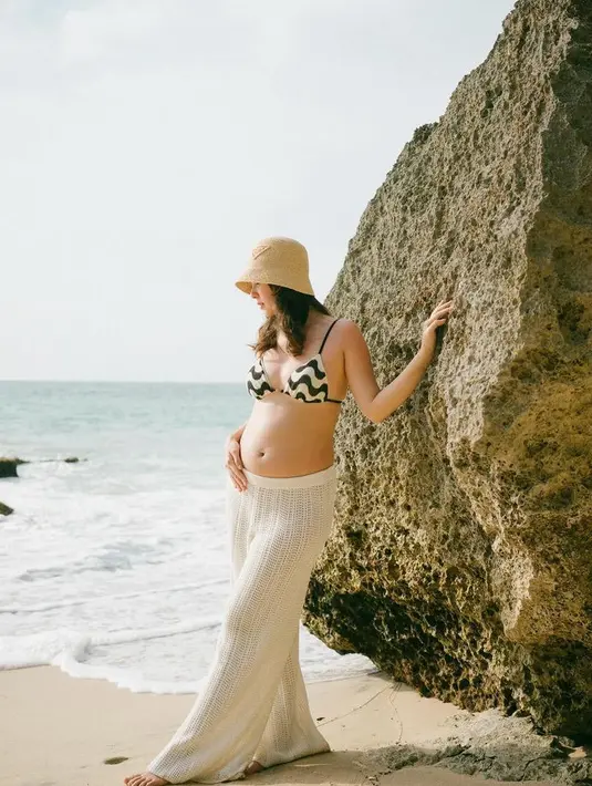 Berlibur ke Bali, Pamela memerlihatkan baby bumpnya. Ia mengenakan atasan bikin hitam putih dipadukan celana knit putih dan bucket hat nya. 