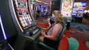 Jodi Williams bermain mesin slot saat pembukaan kembali hotel dan kasino Bellagio, Las Vegas, Nevada, Amerika Serikat, Kamis (4/6/2020). Kasino di Nevada diizinkan kembali beroperasi setelah penutupan sementara untuk mencegah penyebaran virus corona COVID-19. (Ronda Churchill/AFP)
