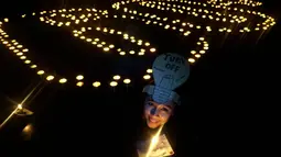 Di Surabaya Seorang wanita tampak memegangi lilin di antara ratusan lilin yang menyala membentuk angka 60. (ANTARA FOTO/Eric Ireng). 