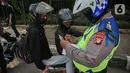 Petugas kepolisian lalu lintas saat menilang pengendara motor saat Operasi Zebra Jaya 2020 di kawasan Cawang, Jakarta, Senin (26/10/2020). Operasi Zebra Jaya dilaksanakan pada 26 Oktober-8 November 2020 untuk menekan jumlah pelanggaran lalu lintas. (Liputan6.com/Faizal Fanani)