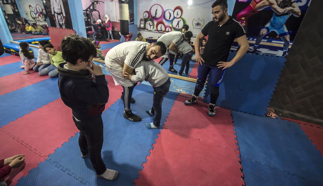 Pengungsi Suriah Amir al-Awad (kaos putih) memprakterkan gerakan kepada siswanya di Akademi Olahraga Suriah di Alexandria, Mesir (4/1). Akademi ini dibangun sejak 2016 dan pendirinya seorang pengungsi Suriah. (AFP/Khaled Desouki)
