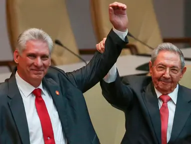 Presiden baru Kuba Miguel Díaz-Canel (kiri) dan Presiden Kuba Raul Castro mengangkat tangan mereka di Majelis Nasional, Havana, Kamis (19/4). Raul Castro mengumumkan Wakil Presiden Miguel Diaz-Canel sebagai penggantinya. (Alexandre Meneghini/Pool via AP)