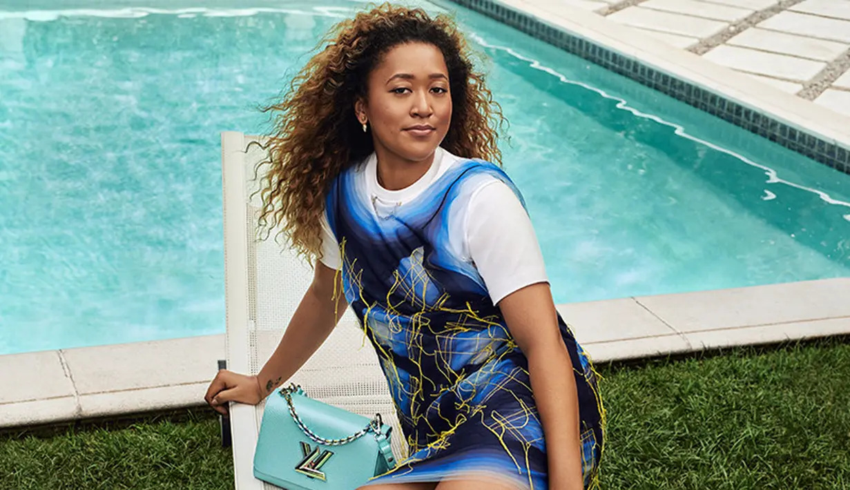 Adalah LV Twist Bag terbaru yang dipromosikan Naomi Osaka di kampanye terbaru Louis Vuitton. Dalam potret ini ia mengenakan print shirt dress dengan warna putih biru lengkap dengan motif rantai emas. Outfit ini dipadukan dengan LV Twist Bag berwarna biru aqua yang serasi dengan latar foto. (Louis Vuitton)