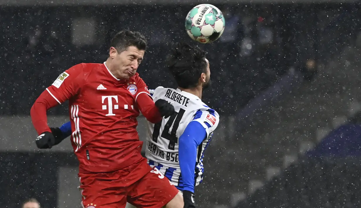 Penyerang Bayern Munchen, Robert Lewandowski dan bek Hertha Berlin, Omar Alderete melompat saat berebut bola dalam ajang Bundesliga 2020/2021 pekan 20 di Olympiastadion, Sabtu (6/2/2021) dini hari WIB. Bayern Munchen menang dengan skor 1-0 atas tuan rumah Hertha Berlin. (John MacDougall/pool via AP)