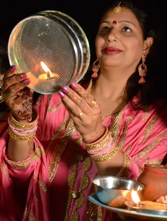 Seorang wanita Hindu yang sudah menikah memanjatkan doa selama festival Karva Chauth di Amritsar,  Kamis (17/10/2019). Karva Chauth merupakan festival di mana wanita-wanita yang sudah menikah di India akan berpuasa dan memohon umur panjang serta keselamatan untuk suami mereka. (NARINDER NANU/AFP)