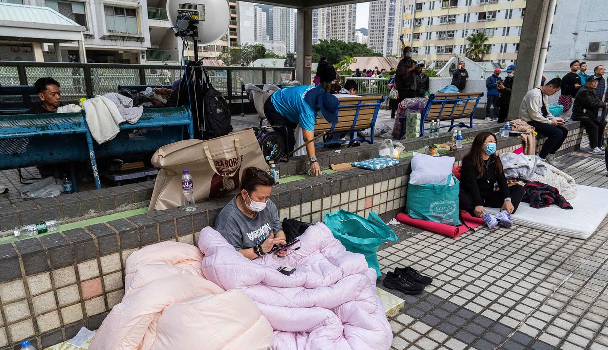 Jumlah korban meninggal dan kritis maupun mengungsi terus diperbarui pihak berwenang setempat seiring berlangsungnya operasi di lapangan. Tampak dalam foto, warga beristirahat di dekat lokasi kebakaran yang terjadi pada hari Rabu di Wang Fuk Court, sebuah kompleks perumahan di distrik Tai Po, Wilayah Baru Hong Kong, Kamis 27 November 2025. (AP Photo/Chan Long Hei)