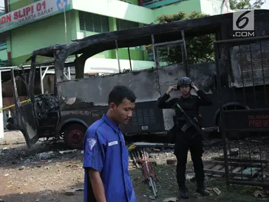 Pasukan Brimob bersiaga dekat bangkai sebuah bus yang terbakar di sekitar asrama Brimob Jalan KS Tubun, Petamburan, Jakarta Barat, Rabu (22/5/2019). Diketahui kerusuhan terjadi di lokasi tersebut, buntut demo depan gedung Bawaslu yang berujung ricuh. (Liputan6.com/Faizal Fanani)