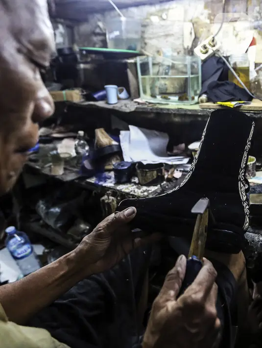 Pekerja menyelesaikan pembuatan sepatu di industri rumahan daerah Kuningan, Jakarta Selatan, Jumat (22/1/2020). Pemilik industri sepatu rumahan ini mengaku selama pandemi omzet berkurang hingga 70 persen. (Liputan6.com/Johan Tallo)