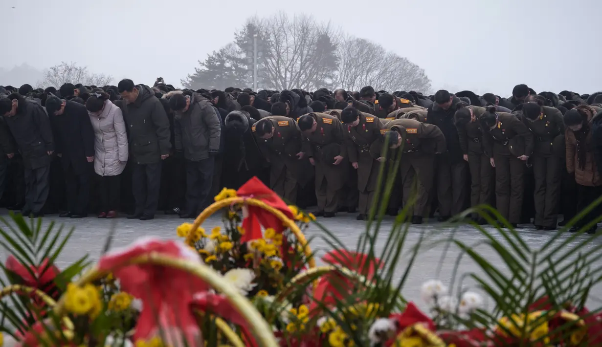 Penduduk Pyongyang memberi hormat di hadapan patung pemimpin Korea Utara Kim Il Sung dan Kim Jong Il selama Hari Peringatan Nasional di Bukit Mansu, Pyongyang (17/12).  Korea Utara tengah memperingati 7 tahun wafatnya  Kim Jong Il. (AFP Photo/Kim Won Jin)